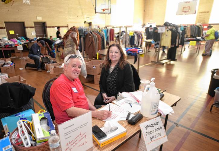 Employees George Funk and Susan Holmquist check people in at the free clothing store at Franklin County’s YMCA in Greenfield on Tuesday.