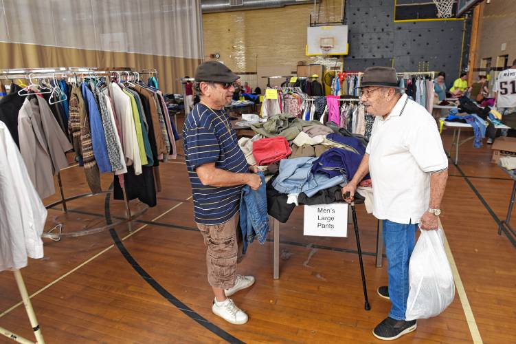 Hector Torres Jr. and Hector Torres Sr., both of Greenfield, browse items at the free clothing store at Franklin County’s YMCA in Greenfield on Tuesday.