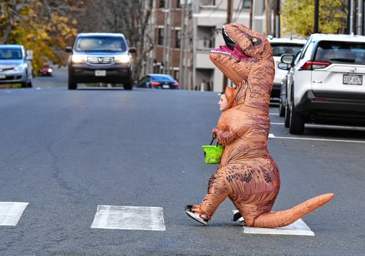 Dinosaurs look both ways to cross the street on Halloween in Greenfield.