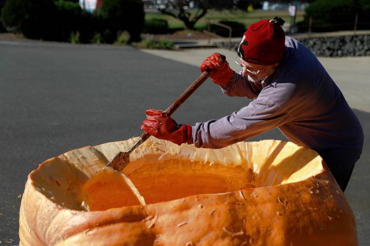 Florence resident Dave Rothstein hallows out a giant pumpkin at Adhesive Applications, where the pumpkin was weighed, Friday afternoon in Easthampton. Rothstein hopes to paddle the pumpkin down the Connecticut River in a world record attempt.