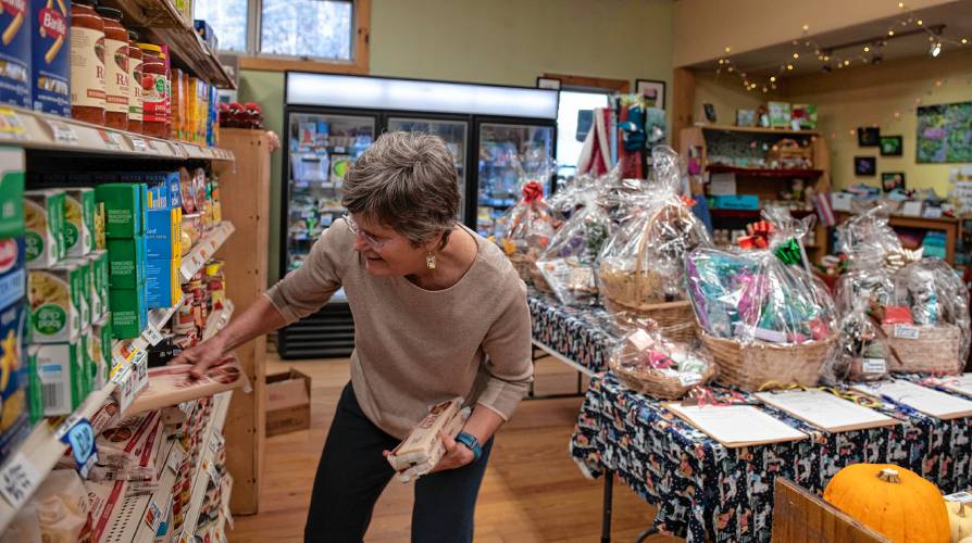 Liz Etheridge, a volunteer at the Leverett Village Co-op, stocks shelves with a recent delivery of food items.