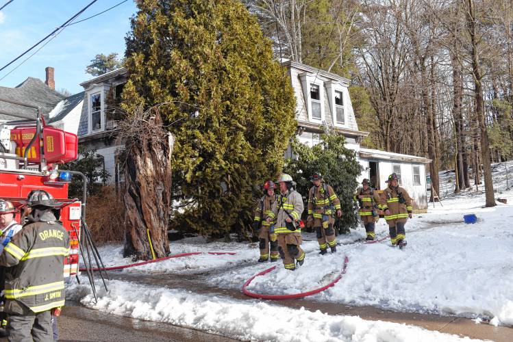 Firefighters exit a two-story, gambrel-style home that was the scene of a fire Wednesday morning on Mechanic Street in Orange.