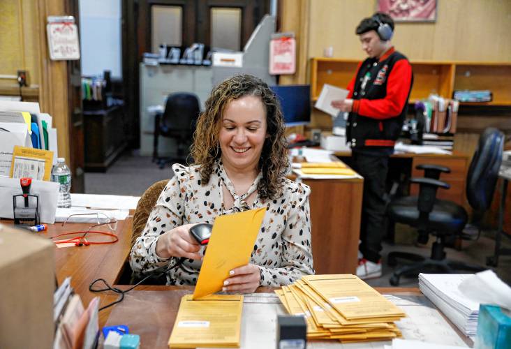 Principal Clerk Jesenia Flores processes received mail-in ballots while temporary worker Jimmy Serrano sends out new ballots Friday afternoon at the Holyoke City Clerk’s Office.