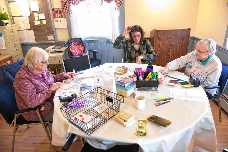 Donna Eddy, Donna Depretto and Phyllis Aldrich make luminaries on Valentine’s Day at the Bernardston Senior Center in honor of late loved ones. The decorated white bags with electric candles in them were set to be displayed in front of the Powers Institute building at dusk.