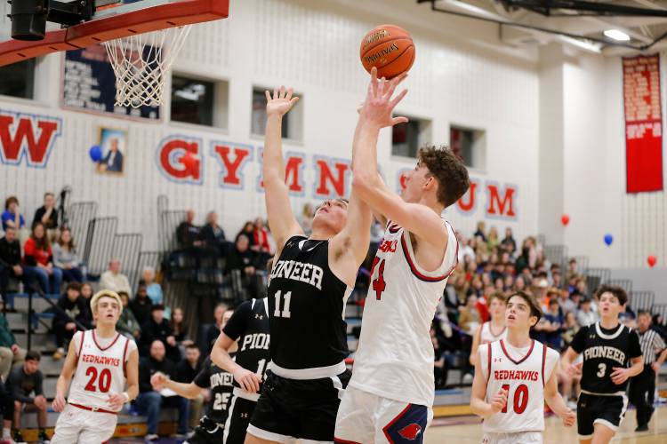 Frontier’s Owen Babb (14) drives to the hoop over Pioneer defender Hugh Cyhowski (11) in the second quarter earlier this season at Goodnow Gymnasium in South Deerfield.