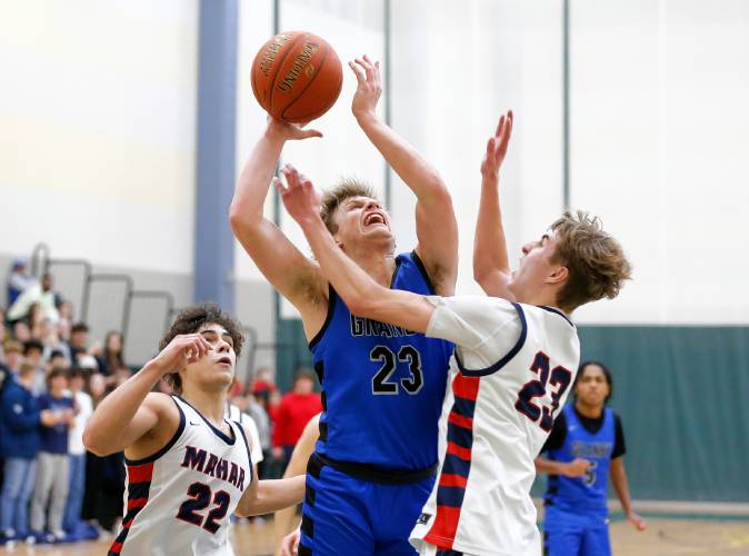 Granby’s Cody White (23) drives to the hoop between Mahar defenders Jayden Delgado (22) and William Barnes (23) in the third quarter of the Western Mass. Class C boys basketball championship Saturday at Holyoke Community College.