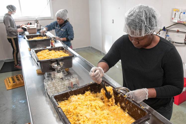 Gillis MacDougall, back left, a worker owner, Marie Maude Joseph, back right, and Katie Desi, employees, package kimchi at Real Pickles in Greenfield.