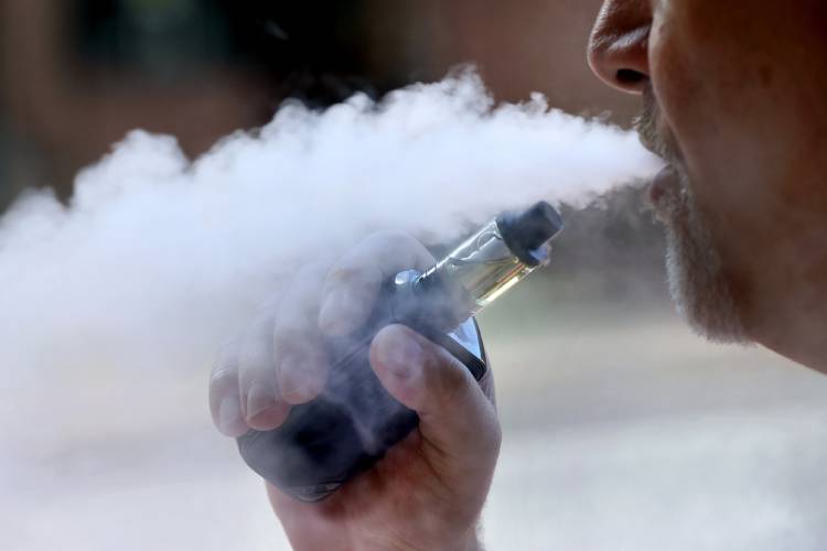 A man exhales while smoking an e-cigarette.