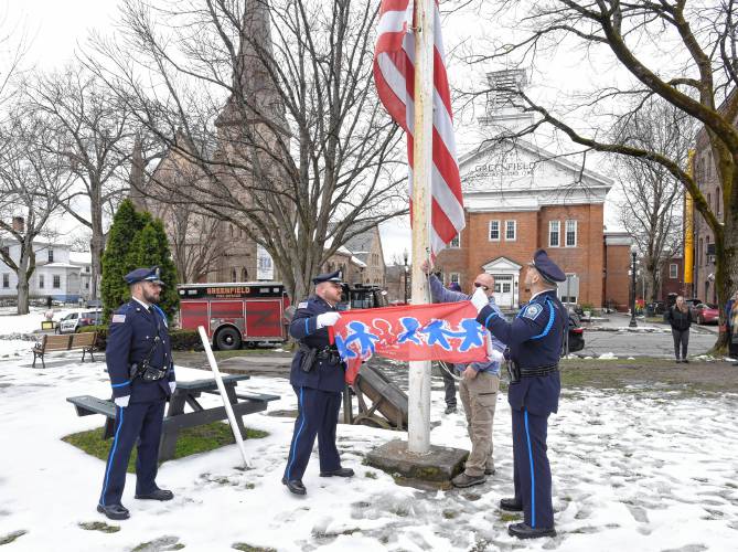 Members of the Greenfield Police Department Honor Guard raise the flag on the Greenfield Common to mark Child Abuse Prevention Month on Friday morning.