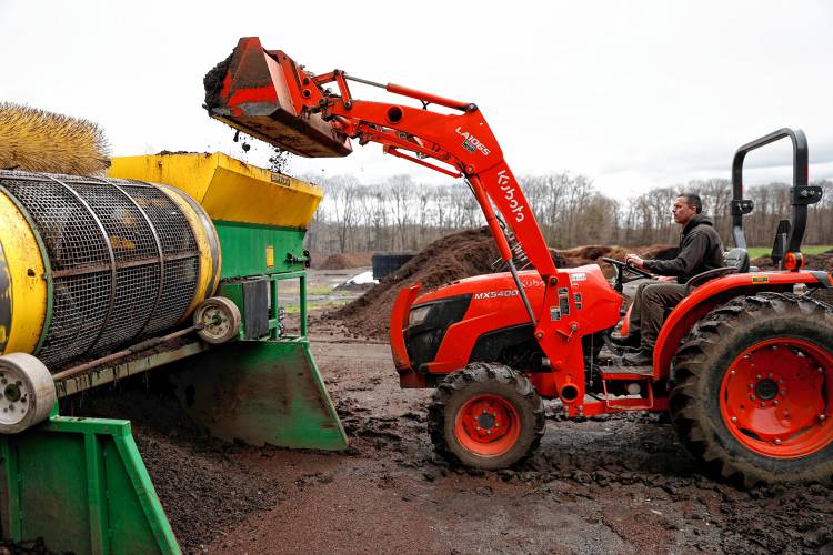 Mark Melnik adds a load of compost into a screening machine on Saturday morning at Bear Path Compost in Whately.