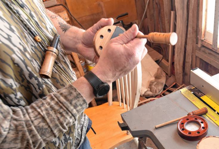 Brandin Coates demonstrates a turkey call, dragging wood across slate mounted to a sounding board.