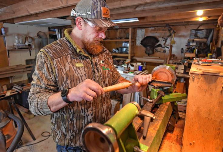 Brandin Coates turns a turkey call on his small wood lathe in his Hawley workshop.