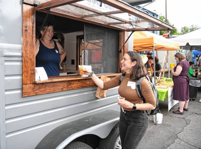 Ericka Almeida of Stout Pigeon Coffee serves an iced coffee to Giorgia Nicolini at the Franklin County Community Development Corporation’s 45th anniversary block party in Greenfield on Thursday.