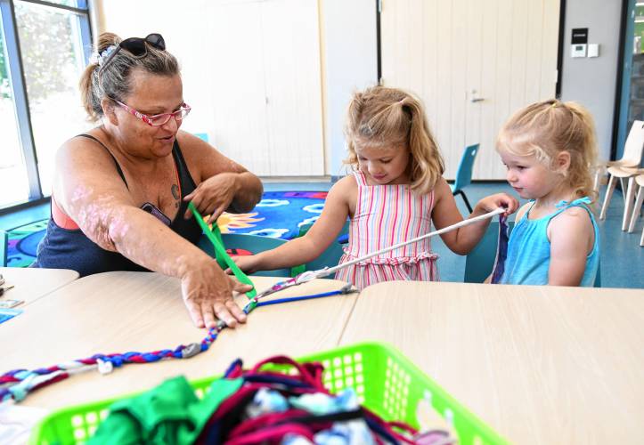 Greenfield resident Mary Lovett helps her granddaughters Lucy Coombs, 6, and Ruthie Coombs, 3, braid fabric scraps into a jump rope in the Children’s Room at the Greenfield Public Library on Tuesday. Another session will be held on Friday, July 19, at 11 a.m.