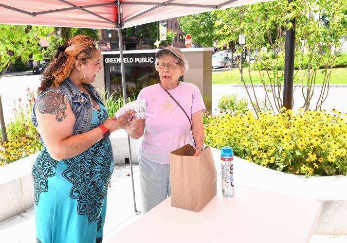 Shaundell Diaz of the Three County Continuum of Care accepts toothbrushes and other items from Doris McLeod of the Church of Saints James and Andrew on Friday during a cooling kit drive at the Greenfield Public Library to support the homeless.