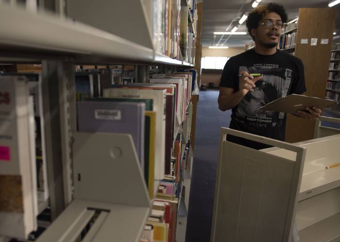 Hilario Peralta, 23, a  Holyoke Community College student, shelves books at the library as his work study job. He says the MassEducate program will help him immensely as he wraps up his studies this fall. 