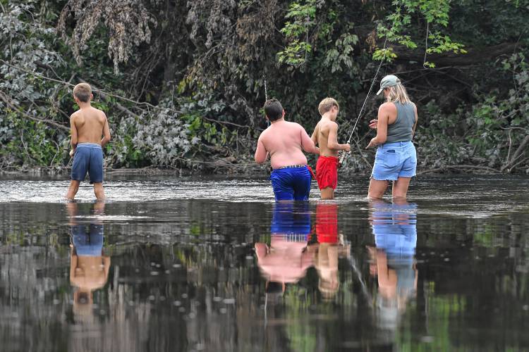 Three young fishermen and their chaperone are reflected in the Deerfield River while casting their lines in Deerfield.