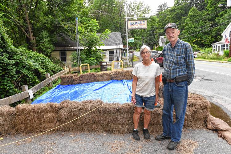 Helen and Robert Baker of Baker’s Country Store stand in what is left of their parking lot. Recent heavy rains eroded the embankment to the South River damaging the lot and septic system and forcing them to remove fuel from their underground tanks as a precaution.