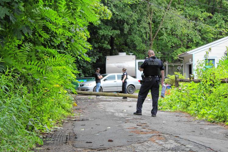 Police stand outside 24 Maple St. in Orange on Friday afternoon after a tree fell on a car, injuring three women who were inside.