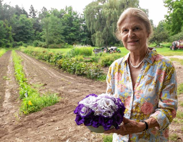 Connie Gillen, co-owner of Sunset Farm in Amherst, holds a bouquet of lisianthus she arranged earlier that day.