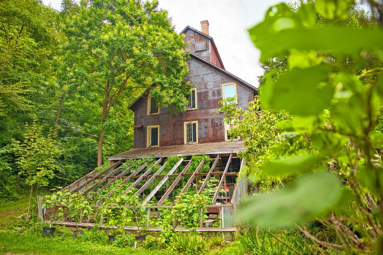 A large greenhouse is part of the remodeled building Jon Lagrèze and Judith Roberts have called home for decades. During winters, the greenhouse is cloaked in three layers of durable, inflatable plastic that stabilizes the cover and insulates well. The couple's home is sided in its original embossed metal.