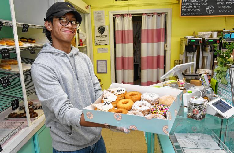 Riches Won Tep with a dozen craft doughnuts at Adams Donuts on Federal Street in Greenfield.