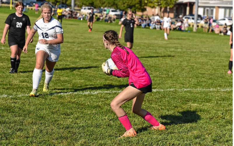 Pioneer goalie Kyler McClelland scoops up a loose ball ahead of a crashing Mady Lynde (12), of Franklin Tech, during the teams’ 0-0 tie in season-opening Bi-County League action on Wednesday in Northfield.