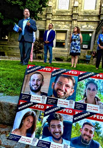 Photos of the six victims were displayed on the sidewalk, with Rep. Aaron Saunders speaking in the background. To the right are Holyoke Mayor Joshua Garcia and Nora Gorenstein of the Jewish Federation of Western Massachusetts.