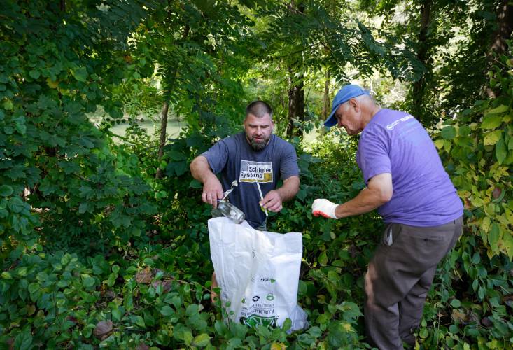 Volunteers Joshua Sonntag, left, and Bill Ashley work to remove trash from the banks of the Green River in Greenfield as part of the Source to Sea Cleanup in 2019. The annual cleanup effort returns Sept. 28.