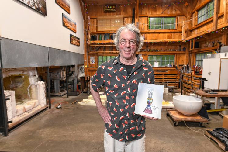 Robert Dane in his Heath studio with the catalog for his exhibit, “Heartbeats and Harmony.”