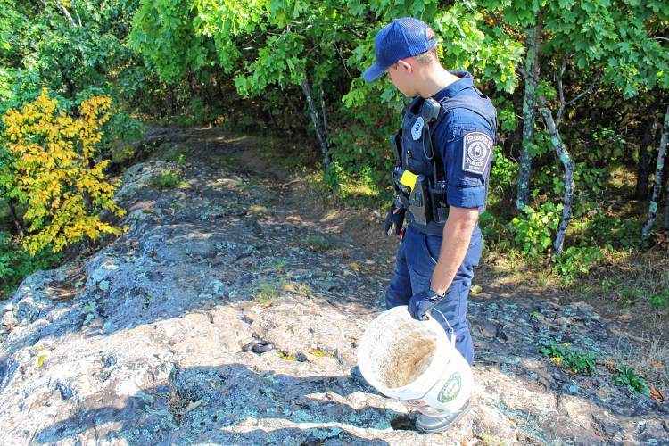 Greenfield Police Officer Marcus Johansson releases a possibly endangered snake near Poet’s Seat Tower in Greenfield on Thursday.