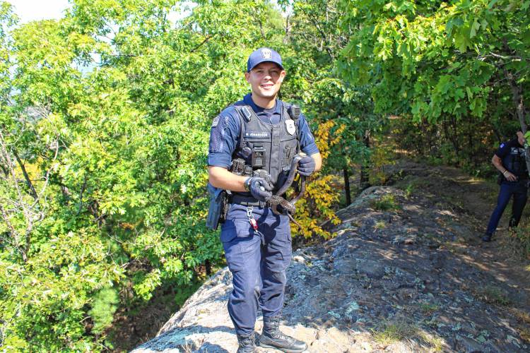 Greenfield Police Officer Marcus Johansson releases a possibly endangered snake near Poet’s Seat Tower in Greenfield on Thursday.