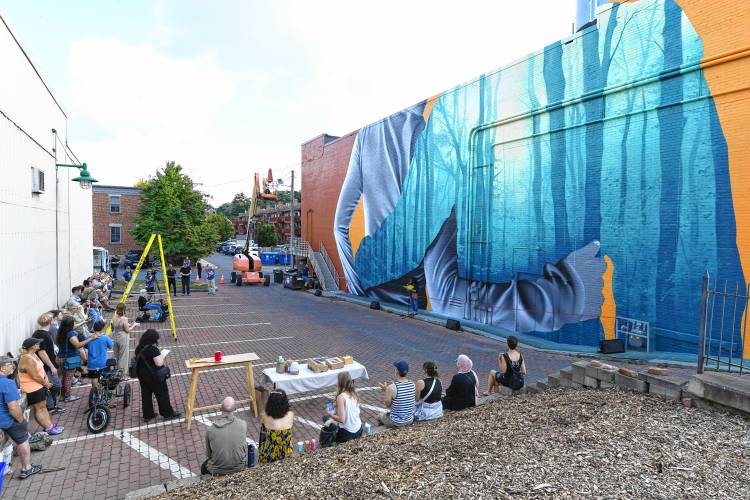 People gather in Turners Falls on Saturday afternoon for a ribbon-cutting ceremony for the mural created by Darion Fleming on the side of the Shea Theater Arts Center.