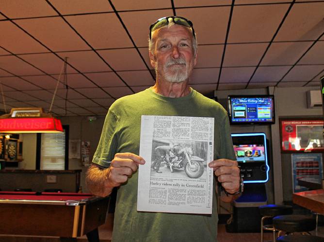 Steve Carroll posing with an old Recorder article where he is pictured alongside his 1990 Heritage Softtail Harley Davidson.