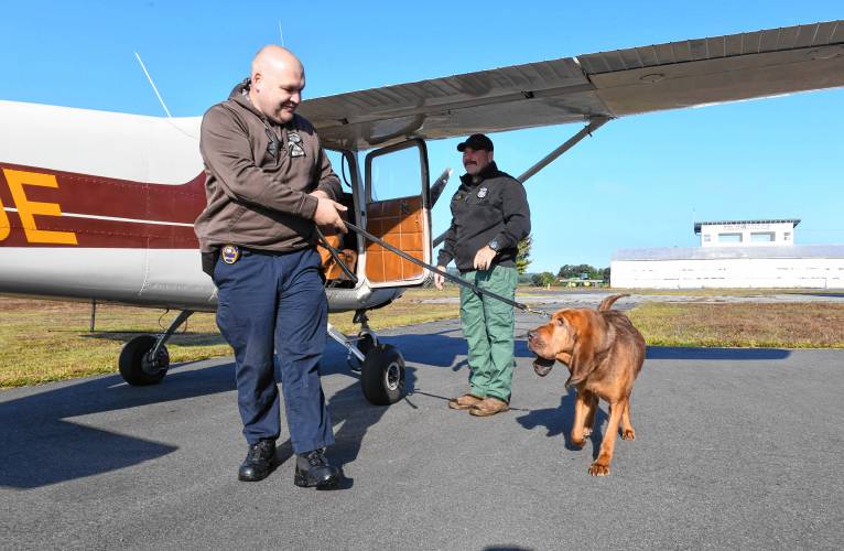 William Figura of the Pawtucket (Rhode Island) Police Department exits a small plane with Neko at the Orange Municipal Airport on Monday, where the Northeast Houndsmen organized training exercises for tracking dogs and their handlers. 