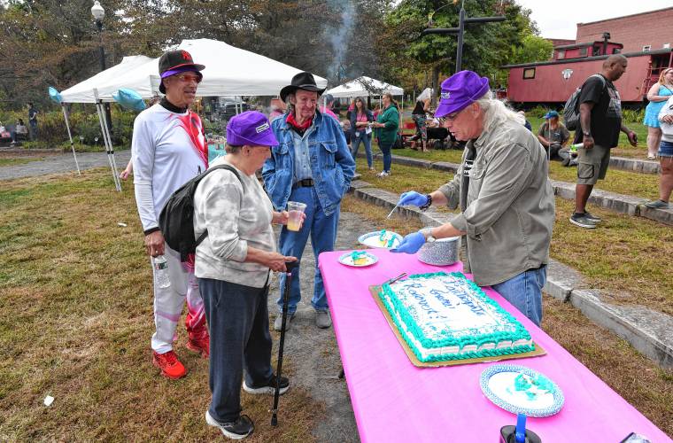 Trevor Dayton, right, of the Northampton Recovery Center, cuts the cake at The RECOVER Project’s celebration of National Recovery Month at Energy Park in Greenfield on Friday, Sept. 20.