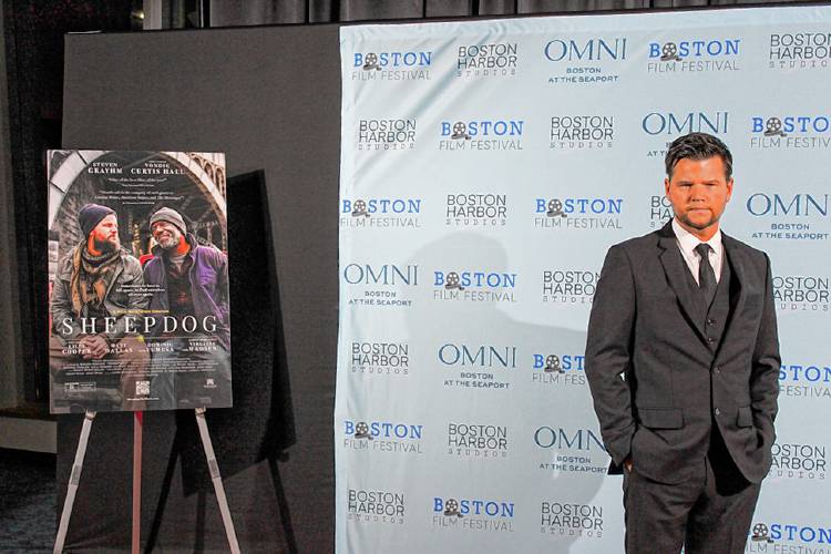 “Sheepdog” writer and director Steven Grayhm pictured next to the official movie poster featuring his character Calvin Cole (left) and Whitney St. Germain (played by Vondie Curtis-Hall).