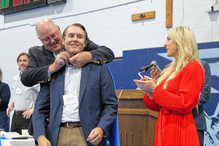 Northwestern District Attorney David Sullivan puts on Children’s Advocacy Center Executive Director Jeff Trant’s superhero cape at the Franklin County Chamber of Commerce’s “Super Chamber Breakfast” on Friday at Franklin County Technical School.