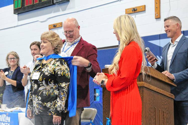 LifePath Executive Director Gary Yuhas puts a cape on LifePath Resource Consultant Terri Letourneau, as Letourneau was honored at the Franklin County Chamber of Commerce’s “Super Chamber Breakfast” on Friday at Franklin County Technical School.