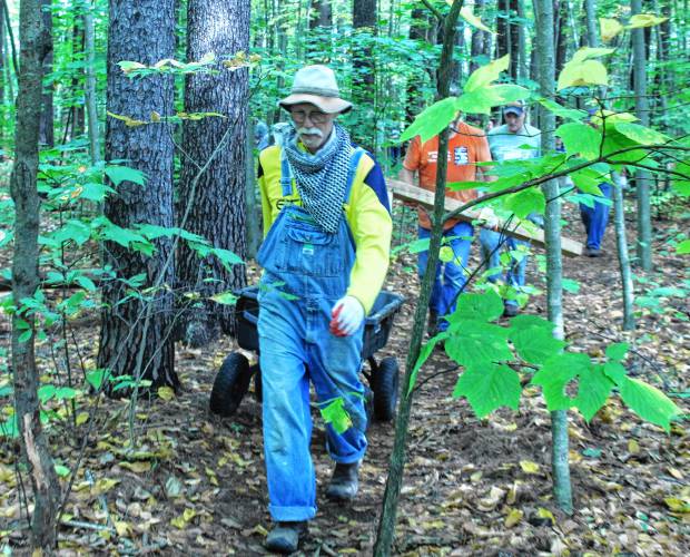 Volunteer Patrick McGreevy carts debris out of the woods at Green River Cemetery off Wisdom Way in Greenfield as part of the 28th annual Source to Sea Cleanup on Saturday.