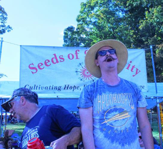 Greenfield resident Chris Weeks, right, reacts after eating his 25th garlic clove to win the raw garlic-eating contest at the North Quabbin Garlic and Arts Festival in Orange on Saturday. Josh Habib, left, brother of festival co-founder Deb Habib, emceed the contest.