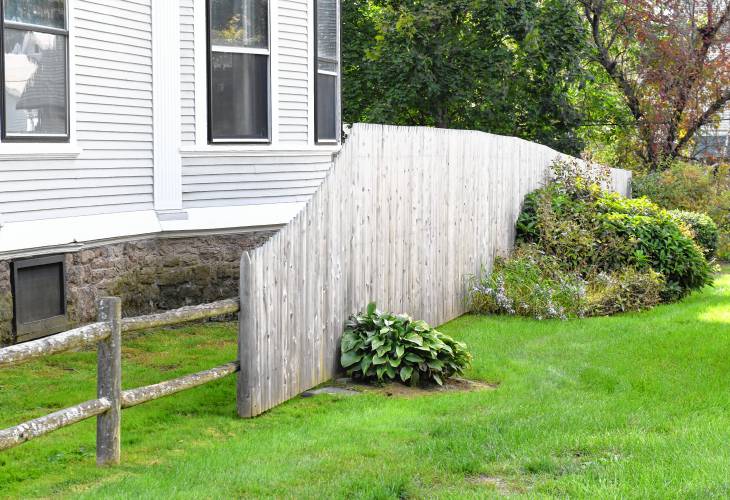 A boundary fence transitions to a privacy fence between two properties in Greenfield.