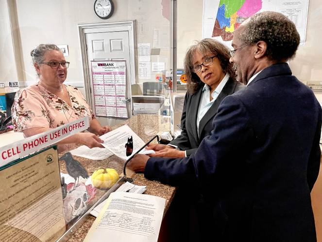 Greenfield residents Joan Marie Jackson and Mitchell Speight hand off a petition, signed by 110 residents, seeking to regulate accessory dwelling unit production in Greenfield at the City Clerk’s Office on Monday.