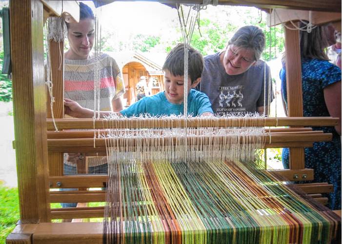 Accompanied by Tonya Jones, at left, and Rachelle Ackerman, at right, Alden tries his hand at weaving during a previous Barnfest in Shelburne. The annual event will be held Saturday, Oct. 5, at 1 p.m.