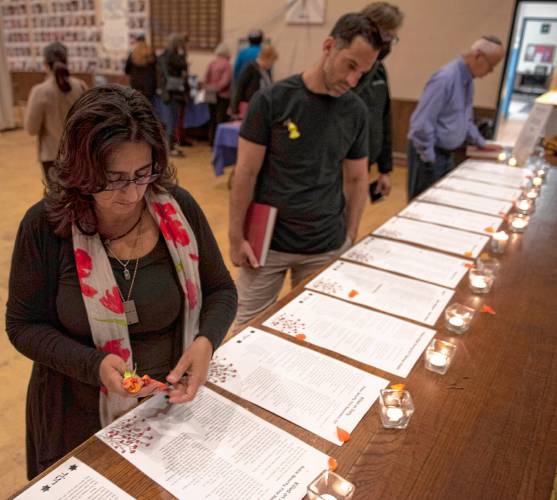 Rabbi Riqi Kosovske of the Beit Ahavah, the reform synagogue of greater Northampton, lights candles around lists of the victims who died in the Oct. 7, 2023 Hamas attack against Israel at a commemoration Monday at Congregation B’nai Israel in Northampton. 