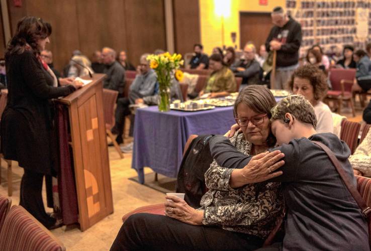 Leah Finch and Alex Carter-Ray listen as Sari Fein reads names of those who died in the Oct. 7, 2023 Hamas attack against Israel at a commemoration Monday at Congregation B’nai Israel in Northampton.