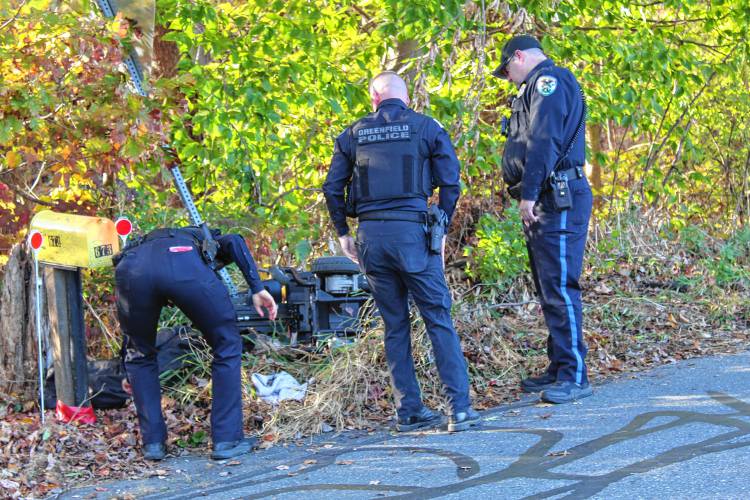 Greenfield Police officers and Franklin County Sheriff’s Office deputies move the wheelchair of one of the two women struck by a vehicle on Country Club Road in Greenfield on Friday afternoon.