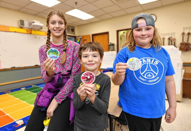 From left, Iris, grade six, Cole, grade one, and McKenna, grade four, hold their winning designs for “I voted” stickers at Sunderland Elementary School.