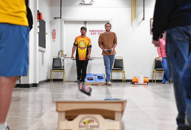 Teams of two, with members at either end, toss 1-pound bags of resin beads at a 6-inch hole on an inclined plane in the Franklin County Baggers cornhole league.