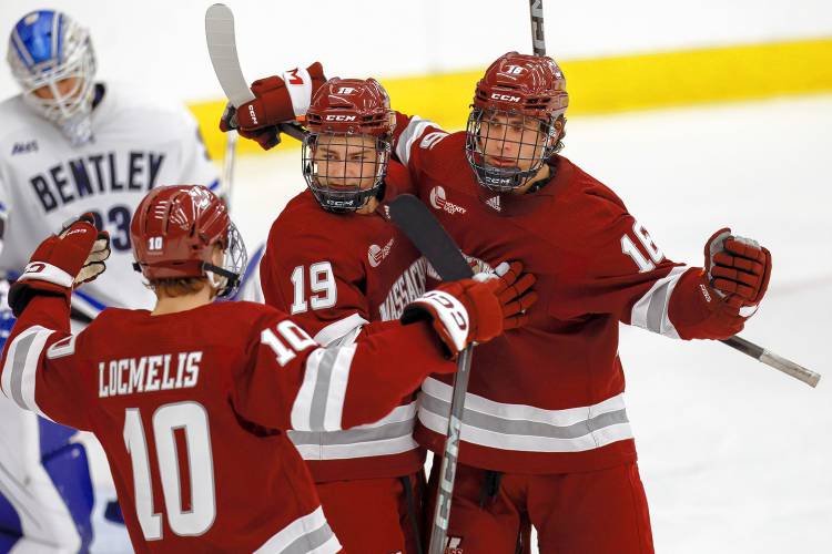 Massachusetts forward Aydar Suniev (16) celebrates with forward Cole O'Hara (19) and forward Dans Locmelis (10) after scoring a goal on Bentley goalie Connor Hasley (33) during the second period of an NCAA hockey game on Saturday, Oct. 5, 2024, in Waltham, Mass. (AP Photo/Greg M. Cooper)